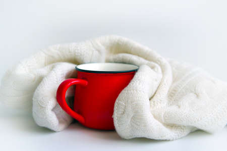 Red mug in a white scarf on white backgroundの写真素材