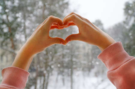 child girl hands show heart in winter outside.の写真素材