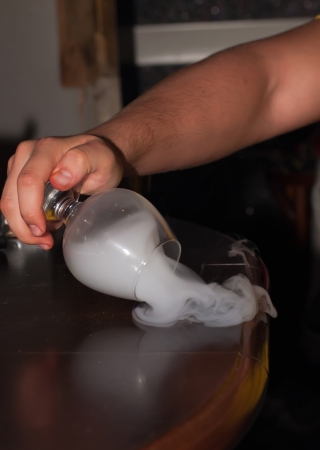 Glass in hand  Smoke flow out from glass to table  の写真素材