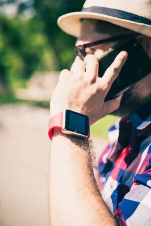 BUCHAREST, ROMANIA, - October 26, 2017: Person using smart watch and a smartphone walking on the park in a sunday. Young man making gestures on a wearable smart watch. Illustrative editorial content.のeditorial素材