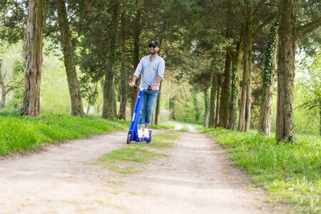 BUCHAREST, ROMANIA, - October 30, 2017: Man using blue electric scooter in the park and in the forest, on a sunny day, with bokeh effect.のeditorial素材