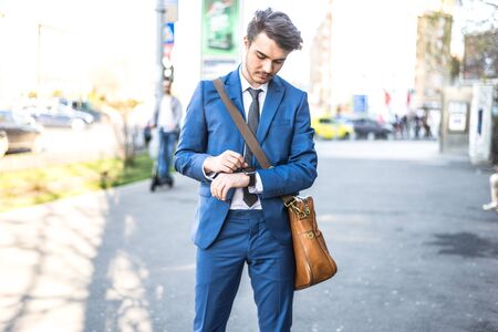 Person using smart watch and a smartphone walking on the park in a sunday. Young man making gestures on a wearable smart watch. Illustrative editorial content.のeditorial素材