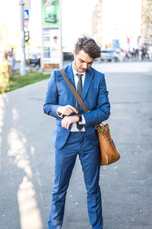Person using smart watch and a smartphone walking on the park in a sunday. Young man making gestures on a wearable smart watch. Illustrative editorial content.のeditorial素材