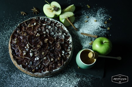 Apple pie with caramel cream on black table with sugar in background and appleの写真素材