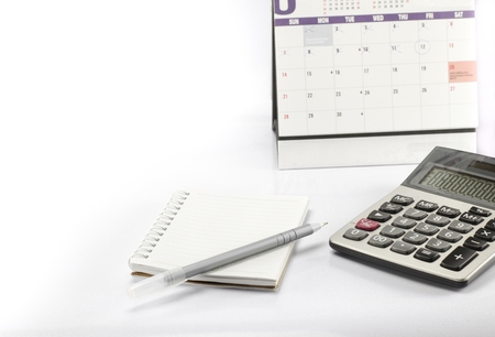calculator and pen and notebook is near calender on white backgroundの写真素材