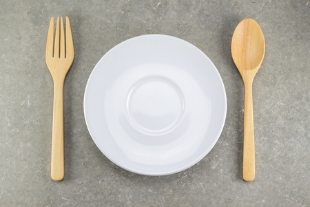 wood spoon and fork with white dish on cement tableの写真素材