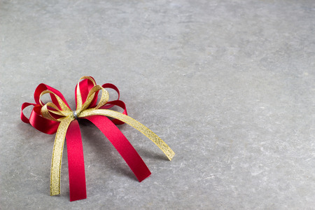 Red and gold bow of ribbon on cement background for fill text in spaceの写真素材