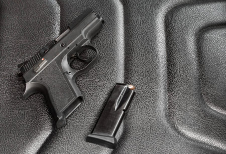 9 mm pistol with magazine and ammunition on the black leather seats. Guns for self-defense.