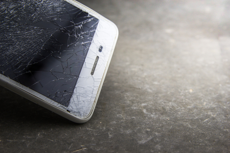 Mobile phone with broken touchscreen on gray background.の写真素材