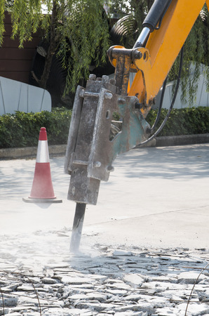 Excavator breaking and drilling the concrete road for repairingの写真素材