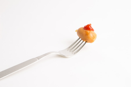 sausage on a fork in front of a white backgroundの写真素材