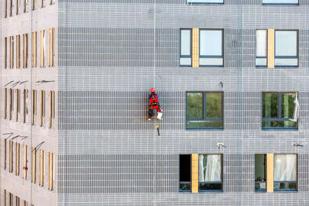 Moscow, Russia - June 6, 2019: Professional industrial climber in helmet and uniform at work, he is washing building facade.のeditorial素材