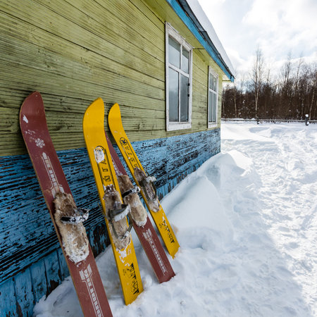 Moscow region, Russia - February 24, 2018: Two pair of old fashioned wooden skis standing near old house on white snow.のeditorial素材