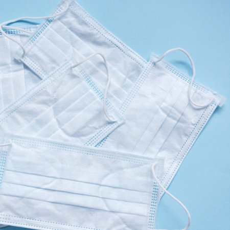 White medical masks on the blue background. Top view.