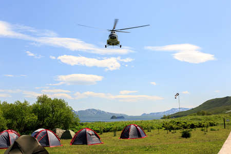 Helicopter is landing near the tent camping in the Kronotsky Reserve near Kuril Lake, Kamchatka Peninsula, Russiaの写真素材