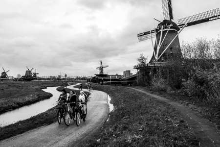 Zaandam, The Netherlands - December 10, 2009: Young women riding bicycles in Zaandam village, North Holland. Bicycle is very popular transport in The Netherlands. Black and white image.のeditorial素材