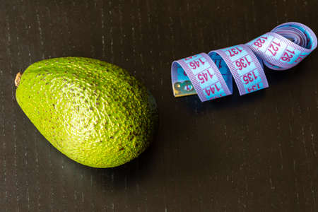 Healthy lifestyle concept, avocado and measuring tape on black backgroundの写真素材