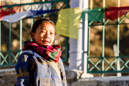 Bhakra, Nepal - November 11, 2015: Portrait of Nepalese girl standing near fence with prayer multicolored flagsのeditorial素材