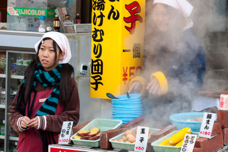 Beppu, Japan - December 29, 2009: Two young girls cooking food on outdoors market. Boiled eggs, corn and potatoes is popular fast food.のeditorial素材