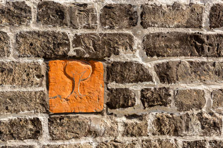 Fragment of gray old stone wall background with one orange brick, part of stone masonryの写真素材