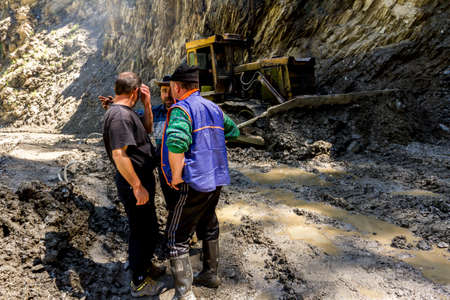Omalo, Georgia - June 11, 2016: Workers with tractor remove the landslide on the mountain road, Tushetiのeditorial素材
