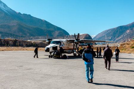 Jomsom, Nepal - November 20, 2017: Airport employees carry luggage to the plane. Jomsom airport in...