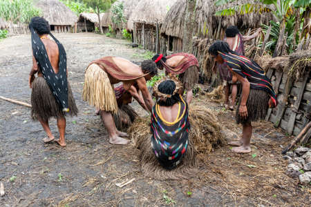 Wamena, Indonesia - January 9, 2010: Dani women cooking food into a hole filled with hot stones. Baliem Valley, Papua New Guinea.のeditorial素材