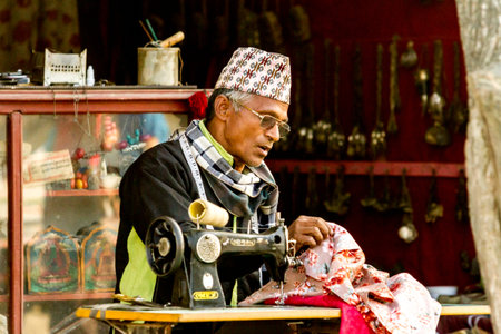 Kathmandu, Nepal - November 5, 2015: Adult Nepali tailor sews on the street. Often to see the people...