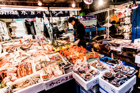 Tokyo, Japan - January 15, 2010: Early morning in Tsukiji Fish Market. Worker laying out fresh fish and seafood on the counter.のeditorial素材