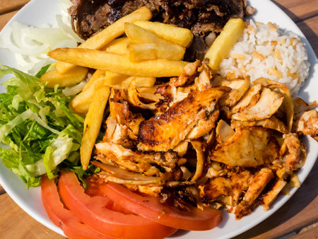 Doner kebab on the plate with french fries, tomatoes, rice, onion and salad. Grilled chicken and...