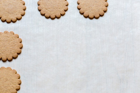 Holiday cookies on baking paper, traditional Christmas treat. Festive background with Ginger cookies. Text space, empty template.の写真素材