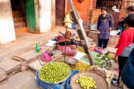 Kathmandu, Nepal - November 5, 2015: Elderly woman sells fruits and vegetables at the street market...