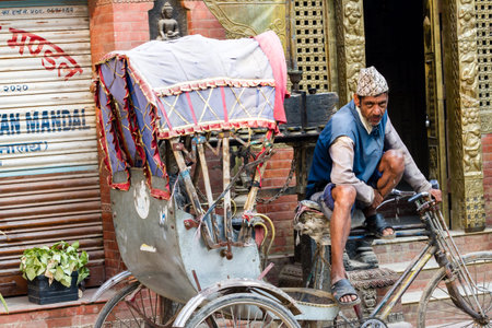 Kathmandu, Nepal - November 17, 2018: Rickshaw driver sitting near his rickshaw on Kathmandu street....