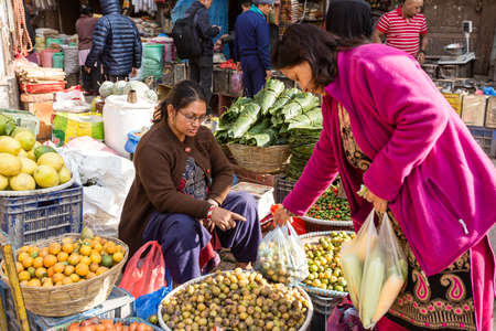 Kathmandu, Nepal - November 17, 2018: Elderly woman buy fruits and vegetables at the street market in Kathmanduのeditorial素材