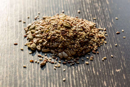 Mixed dry seeds pumpkin, sesame, sunflower, flax for healthy eating on the wooden black table.の写真素材