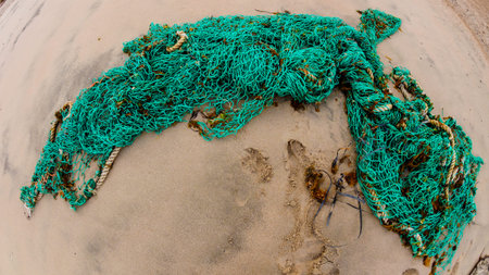 Twisted green fishing net on the sandy shore, top view