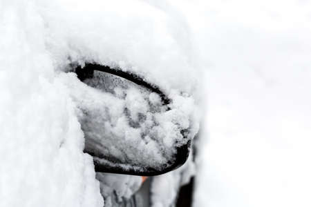Car mirror covered with snow after heavy snowstorm in winterの写真素材