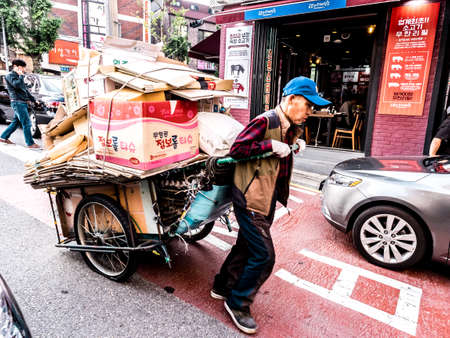 Seoul, South Korea - June 8, 2017: An elderly man carrying the cart with paper trash in the downtown in Seoulのeditorial素材