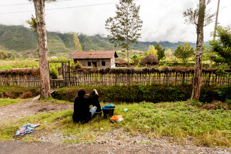 Wamena, Indonesia - January 9, 2010: Dani woman washing clothes on a rural road in the Baliem Valley, Papua New Guinea.のeditorial素材