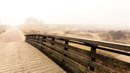 Wooden bridge and road. Autumnal misty morning on the coast of Texel island, the Netherlands.の写真素材