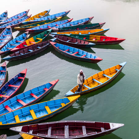 Pokhara, Nepal - November 21, 2015: Man rowing in the colorful boat on Phewa lake in Pokhara.のeditorial素材
