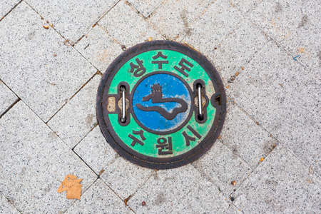 Round green sewer hatch on the street in Seoul downtown, South Koreaの写真素材