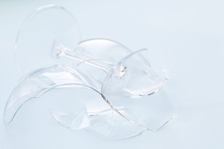 Closeup of broken wineglass on white background for concept design. Shattered glass texture.