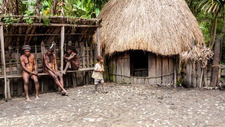 Wamena, Indonesia - January 9, 2010: Men of the Dani tribe in a traditional dress sitting near straw...