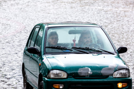 Sighnaghi, Georgia - June 9, 2016: Two people sitting in the car under heavy rain on the street of...