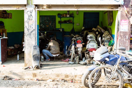 Kathmandu, Nepal - November 4, 2018: Man working in a small bike and motorcycle repair shop in Kathmandu downtown.のeditorial素材
