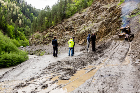 Omalo, Georgia - June 11, 2016: Workers with tractor remove the landslide on the mountain road, Tushetiのeditorial素材