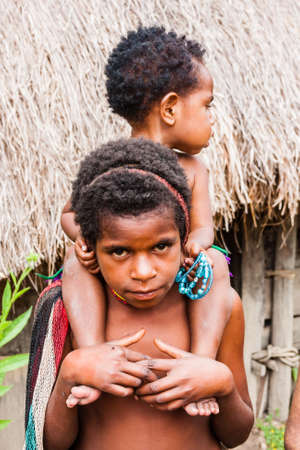Wamena, Indonesia - January 9, 2010: Dani tribe children standing nea straw houses. Baliem Valley in Indonesia, Papua New Guinea.のeditorial素材