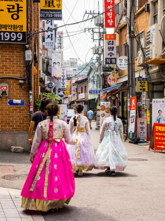 Seoul, South Korea - June 26, 2017: Three young women in colorful traditional wear - hanboks walking down a small street in Seoul downtownのeditorial素材