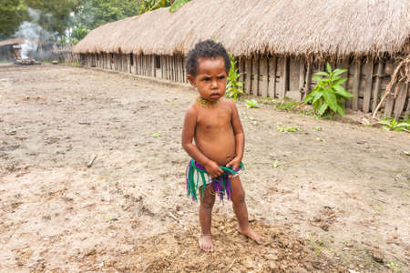 Wamena, Indonesia - January 9, 2010: Dani tribe child standing nea straw houses. Baliem Valley in Indonesia, Papua New Guinea.のeditorial素材